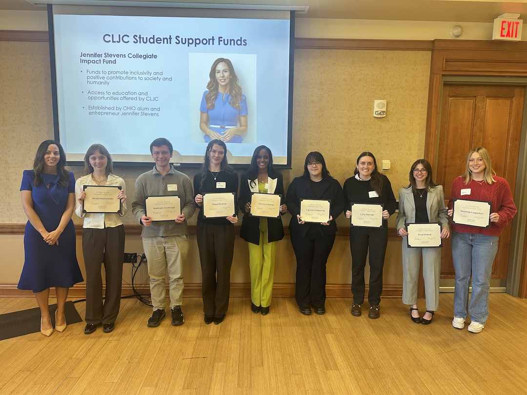 A group of students pictured with an alum as they receive an award and present an alumni funding effort. 