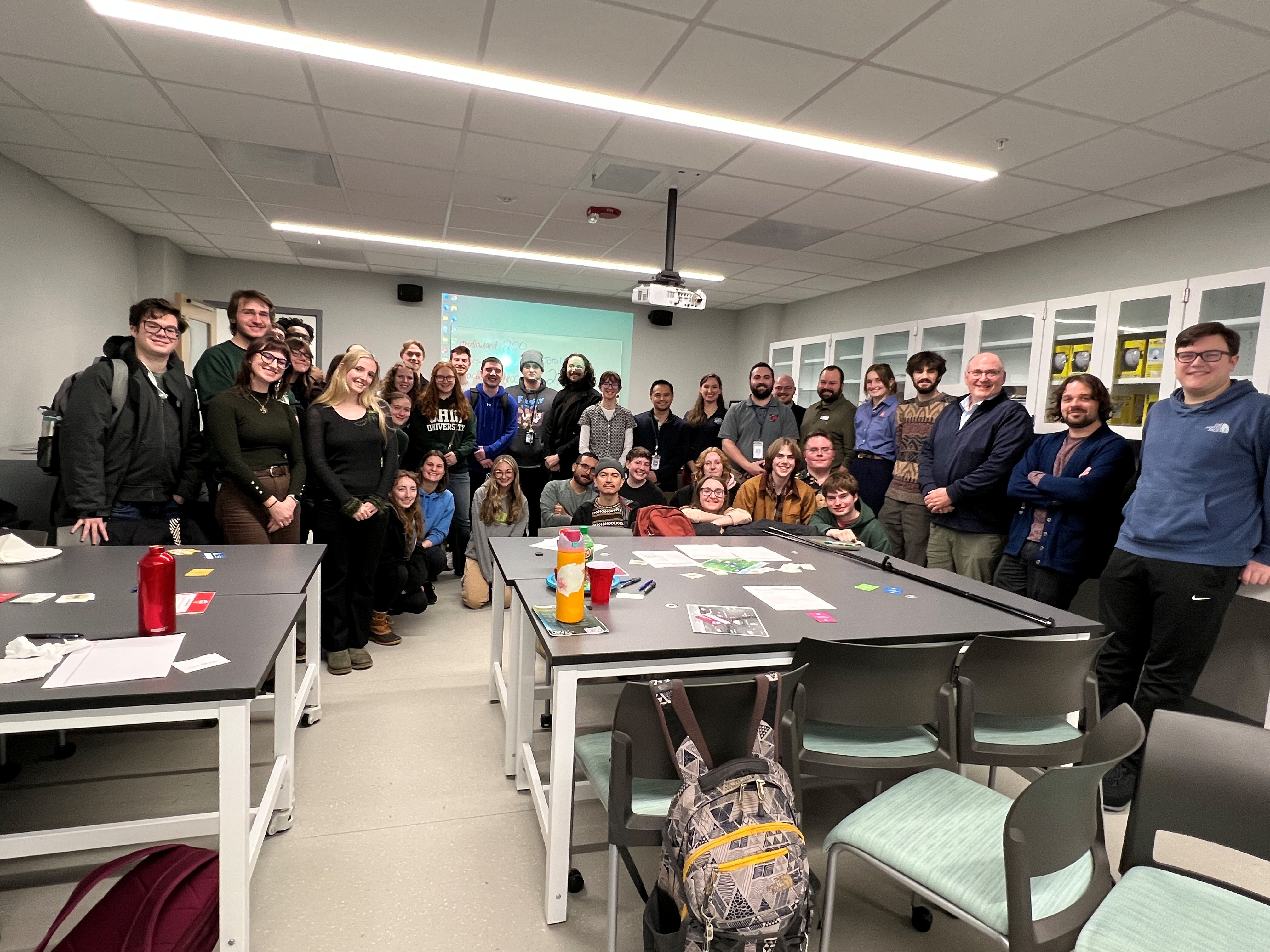 People stand side-by-side in a classroom setting for a large group photo.