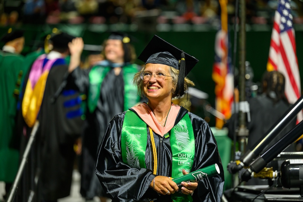 A student smiles up at the crowd at the spring 2026 graduate Commencement ceremony