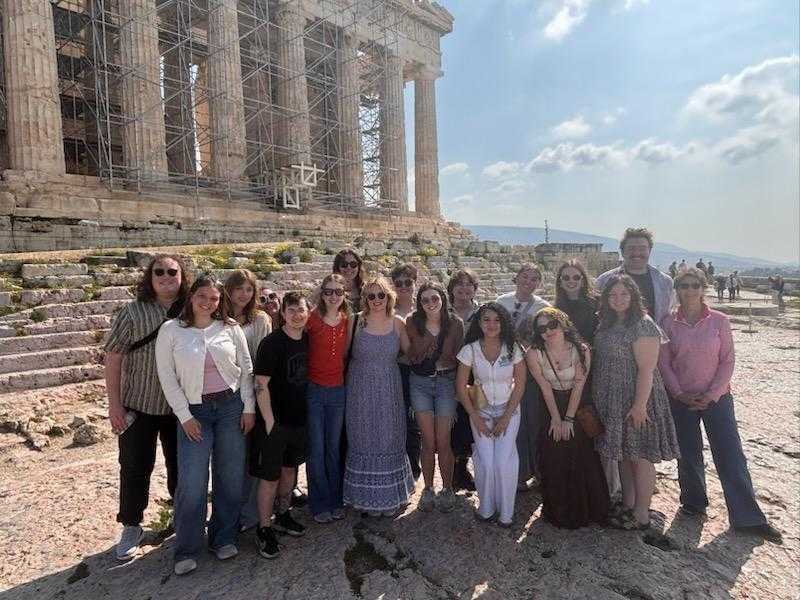 A group of students and faculty pose for a picture in front of a Greek ruin