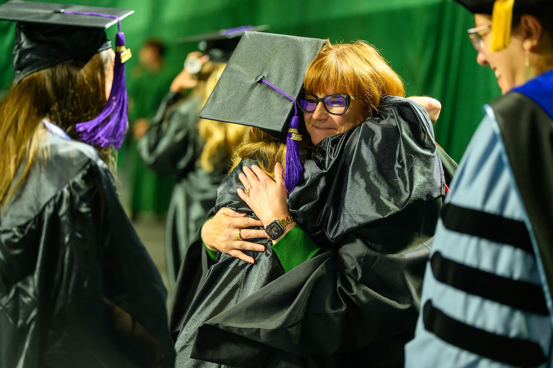 a new graduate receives a hug from a faculty member at the 2026 Spring Commencement ceremony