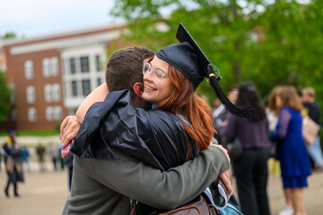 a new graduate gets a hug outside the Convo