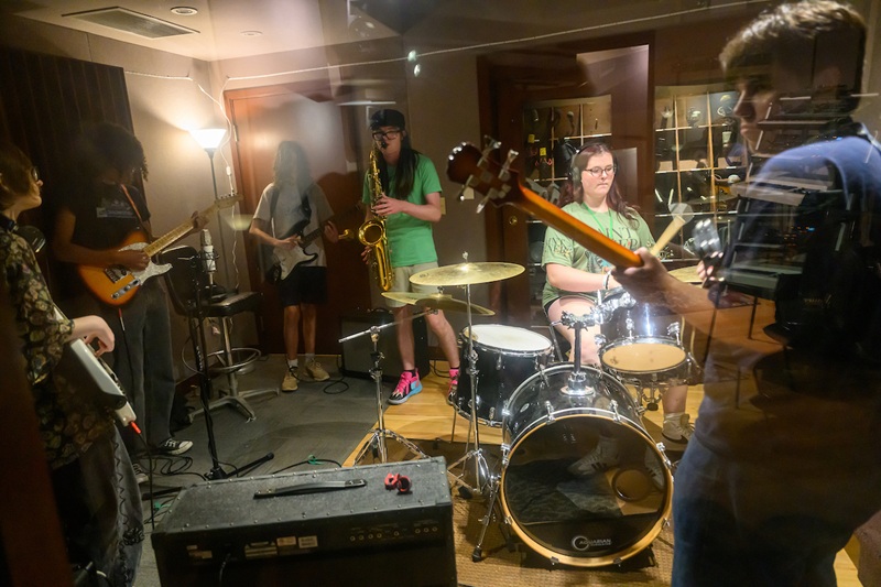 Students at the High School Media Workshop play musical instruments in a recording studio