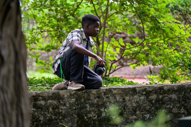 A camp participant holds a camera while waiting to take a photograph on OHIO's College Green