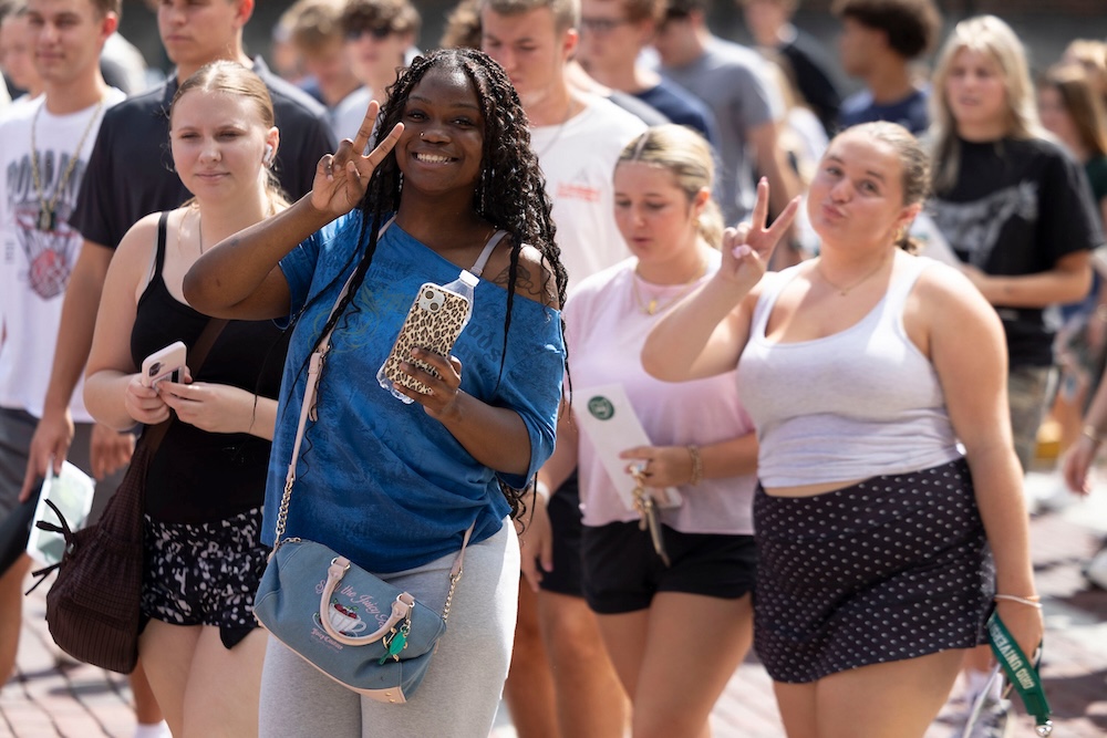 A group of students flash the peace sign at the camera