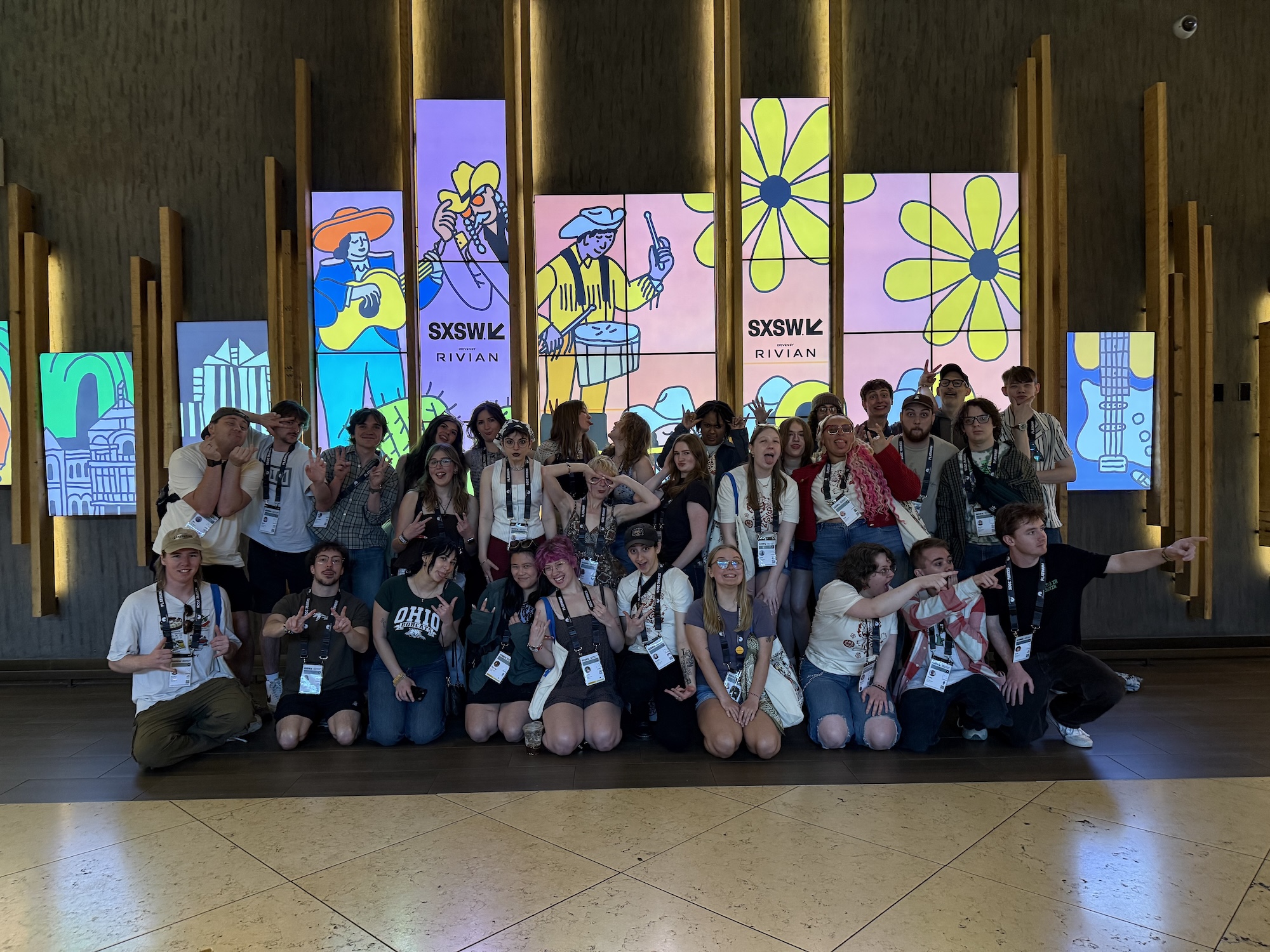 A large group of OHIO students pose for a picture in front of a SXSW sign