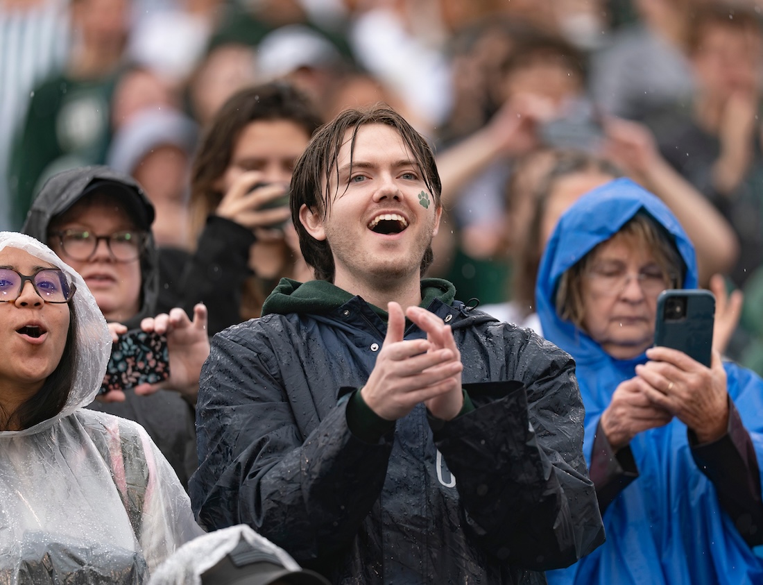 An OHIO fan cheers from the rainy stands during the Homecoming game