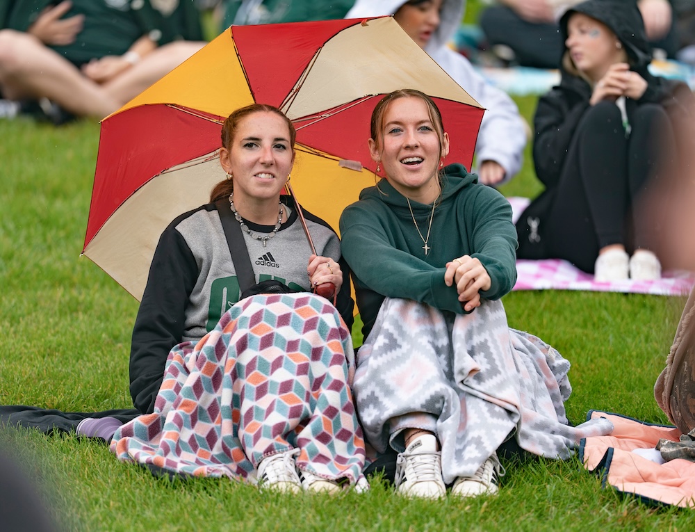 Two OHIO fans sit under an umbrella