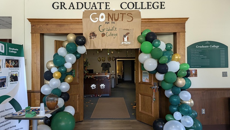 The door to the Graduate College is decorated with green and white balloons and a sign that says Go Nuts for the Graduate College