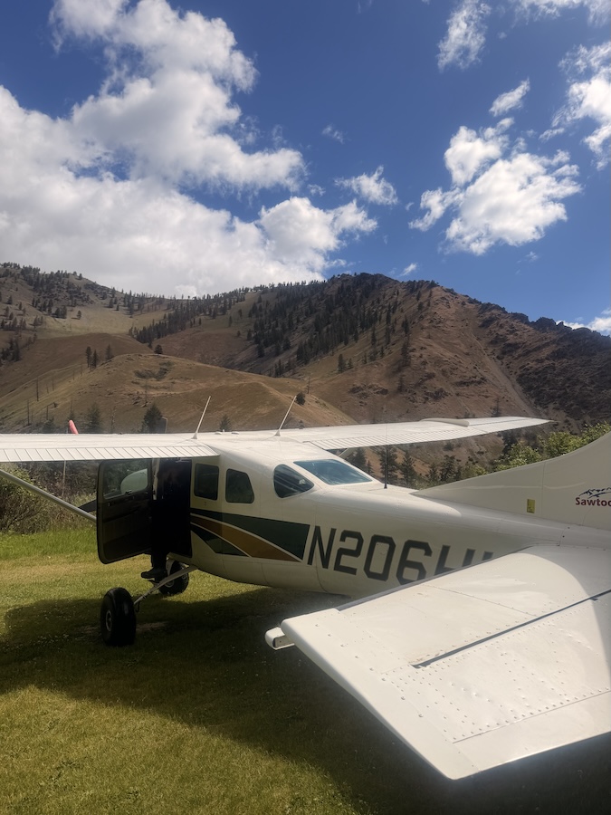 a biplane in a field with mountains in the distance