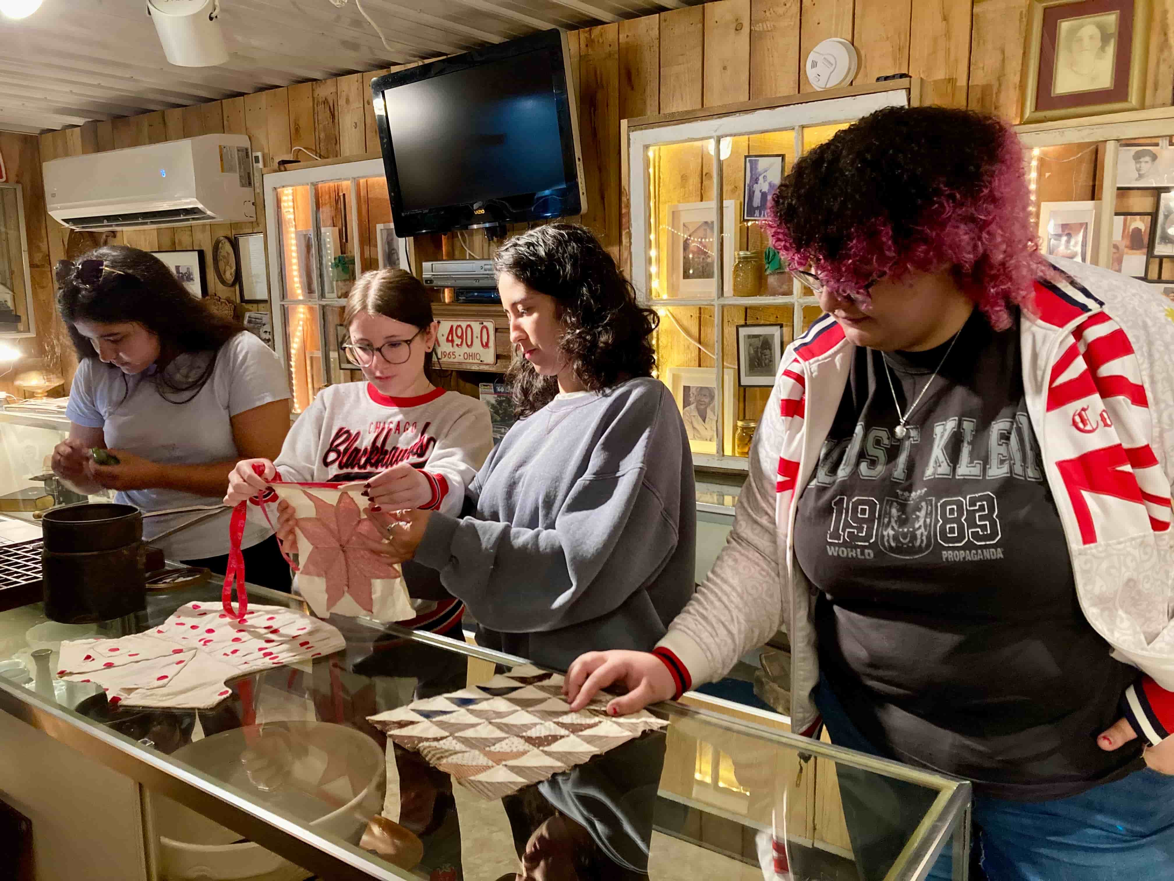 Four students stand at a museum counter looking at documents