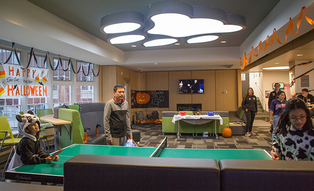 Tao Yuan watches his son Andy Yuan, 8, and daughter Emma Yuan, 11, play ping pong during tRAC-or-Treat in James Hall on Oct. 24.