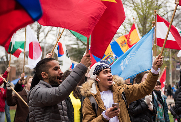 Ohio University student Aziz Al Fadha (right) and his friend wave flags as they listen to the speakers at the International Street Fair.