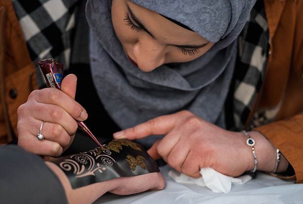 Basair Al Hinai applies a henna tattoo to Adrianna Shafer's hand during the 2018 International Street Fair.