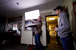 Ohio University alumnus and cinematographer Matt Love, center, discusses lighting setups with OHIO student Elijah Jimenez.