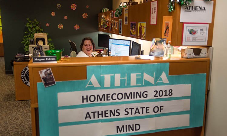 Margaret Cabrera, an administrative services associate in the Office of Community Standards and Student Responsibility, is pictured at the office’s front desk, decorated with a replica of the Athena Cinema’s marquee, proudly displaying the “Athens State of Mind” theme, for Paint the Town Green.