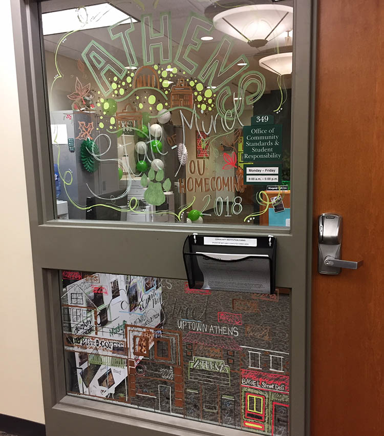 For their Paint the Town Green display, staff in the Office of Community Standards and Student Responsibility decorated the office’s front window with this year’s Homecoming logo and artistic drawings of Court Street businesses.