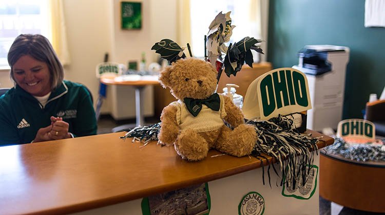 Tammy Andrews, administrative specialist in the Office of the Dean of Students, is pictured with some of her personal OHIO decorations, including a teddy bear, OHIO-themed Passion Works pinwheels and pompoms.