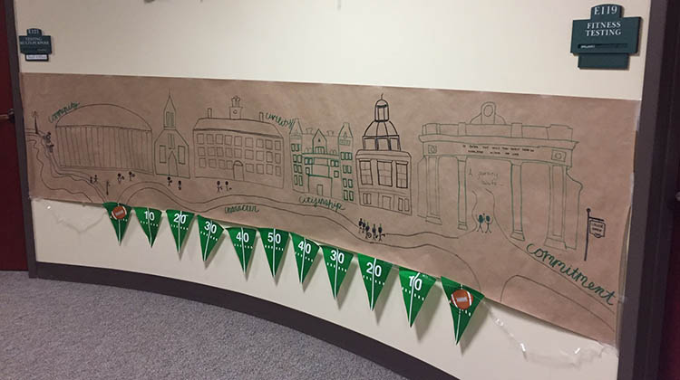 A banner, featuring iconic buildings and landmarks on the Athens Campus as well as OHIO’s five core values, is shown at WellWorks’ Paint the Town Green display. 