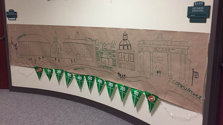 A banner, featuring iconic buildings and landmarks on the Athens Campus as well as OHIO’s five core values, is shown at WellWorks’ Paint the Town Green display.