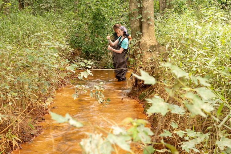 Researchers study Sunday Creek's water quality samples at an acid mine drainage discharge site.