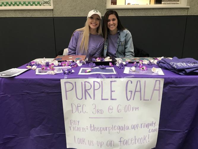 Two nursing students pose at a table promoting the Purple Gala.