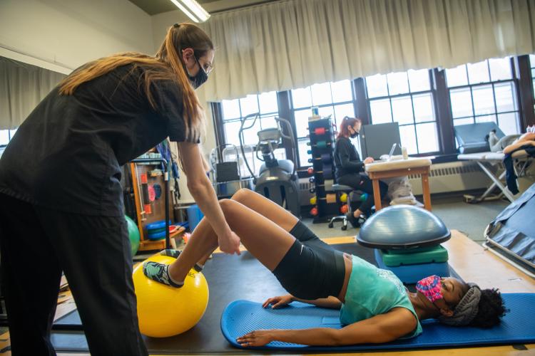 A clinician works with a performing artist using an exercise ball