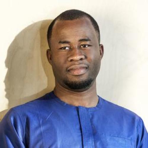Chigozie Obioma wears a royal blue shirt and looks into the camera