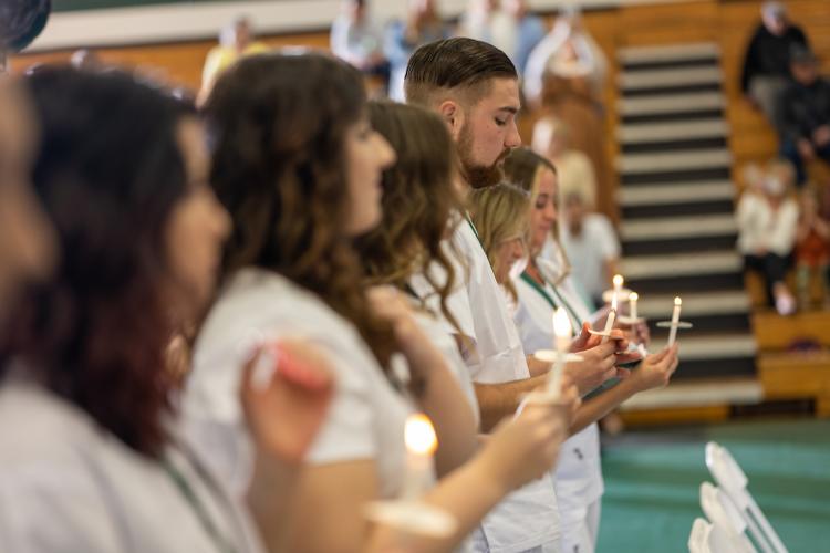 nursing graduates hold candles