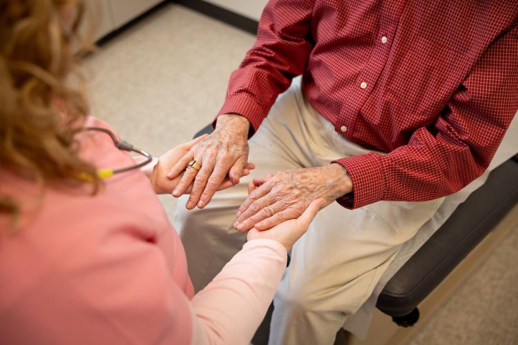 A clinician looks at the hands of an older patient
