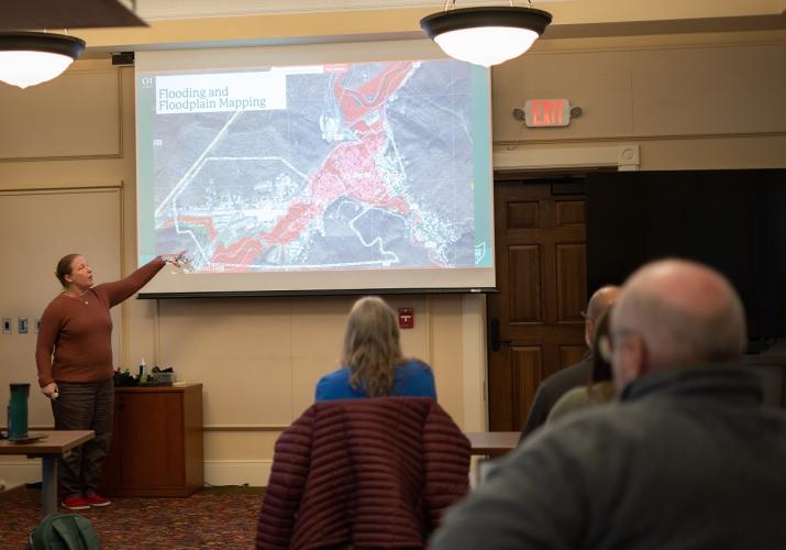 Natalie Kruse Daniels points at a map that says Flooding and Floodplain Mapping during a presentation