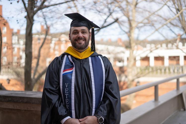 Ryan Stillwell is shown in his Commencement robe and cap while standing outside at Ohio University