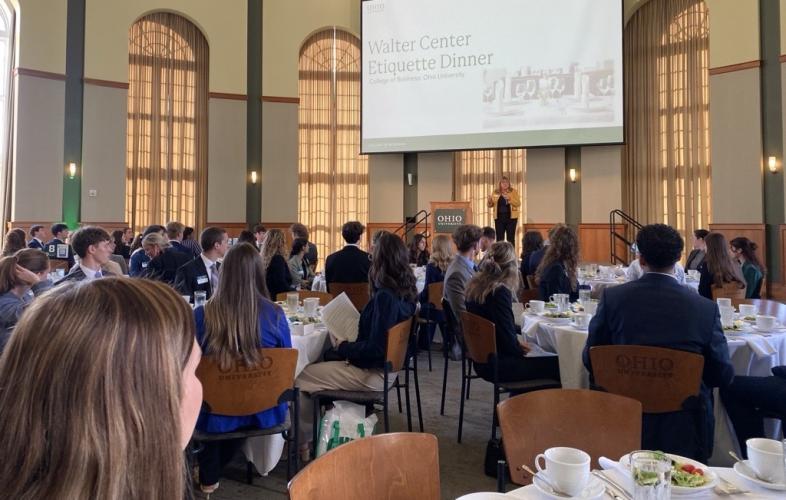 OHIO students and IGS Energy representatives sit at tables and listen to a speaker during the Etiquette Dinner in the Walter Hall Rotunda