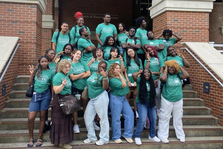 The LINKS Peer Mentors stand together and make silly poses outside while standing on steps