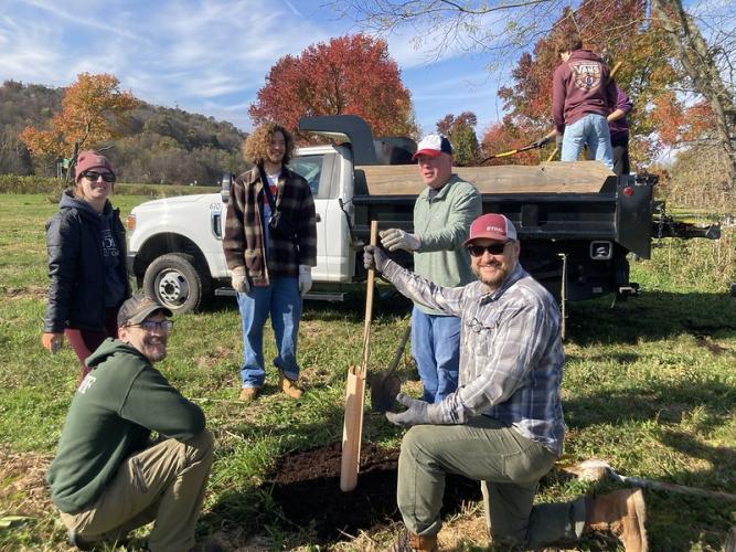 Volunteers pose for a photo in front of a truck and a tree during the tree planting event