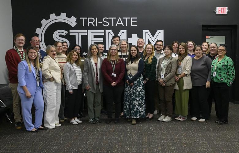 Individuals from regional STEM programs pose for a photo in front a wall that says Tri-State STEM