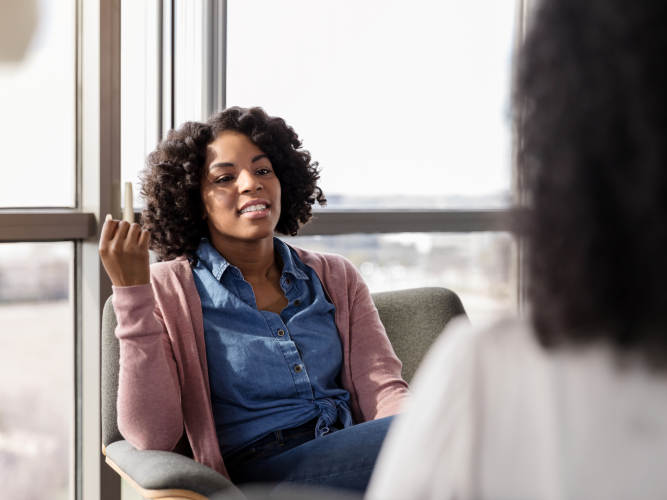 woman sitting in a chair in an office talking to a counselor