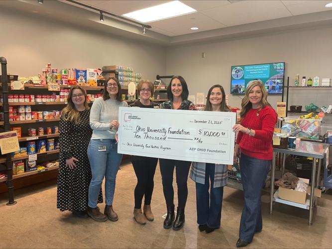 Representatives of Ohio University and the AEP Ohio Foundation hold a giant check while standing in a food pantry