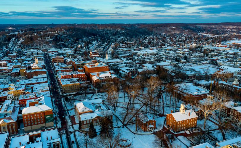 A drone image of Ohio University's Athens Campus, including Cutler Hall and the College Green, with the city of Athens in the background and clouds in the sky