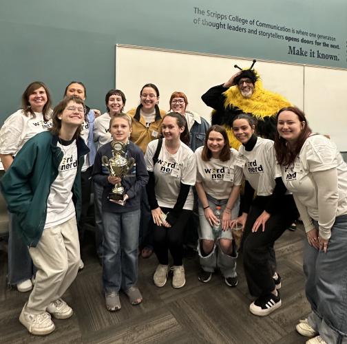 Participants and organizers from a spelling bee competition at Ohio University stand together for a photo. One person is wearing a bee costume.