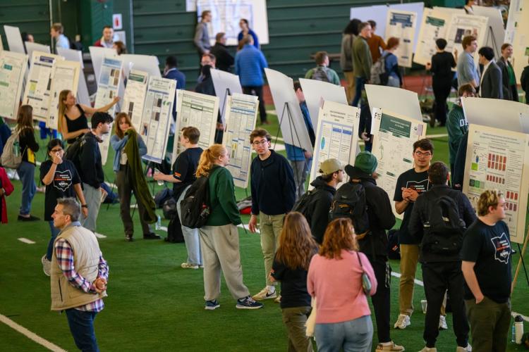 OHIO students stand  in front of their research posters and discuss their work at the Student Research Expo in Walter Fieldhouse