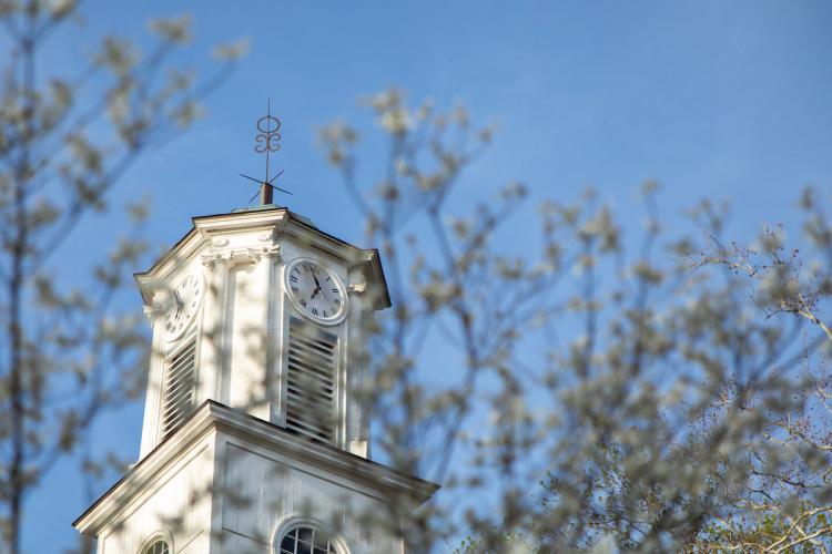 The Cutler Hall Clock is shown surrounded by colorful tree branches on a spring day