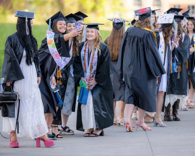 OHIO Lancaster graduates in caps and robes stand together outside for photos and to talk with each other