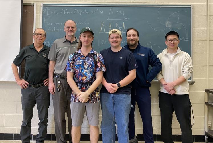 OHIO students, faculty and staff who work with the OSC stand together in front  of a chalkboard in an OHIO classroom