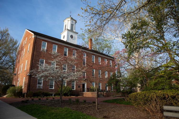 Cutler Hall is shown surrounded by colorful trees on a sunny day in the spring