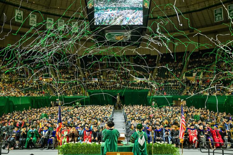 wide shot of Commencement at the Convocation Center as green confetti explodes over the graduating class of 2026