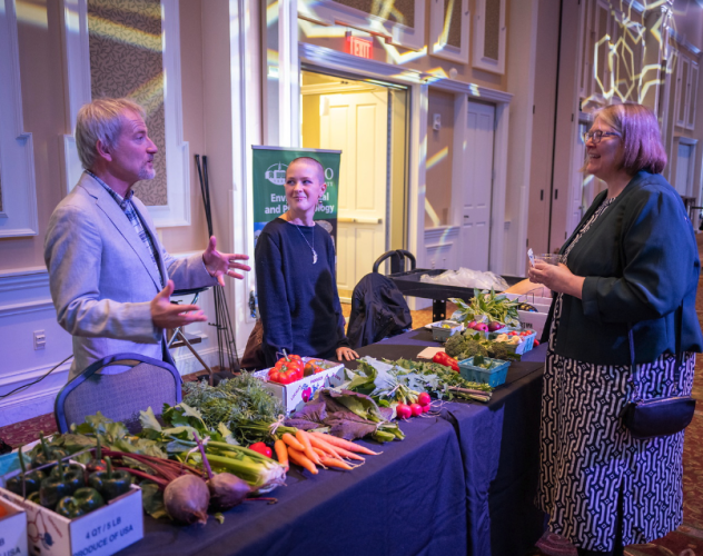 people talking at produce table at environmental impact event 