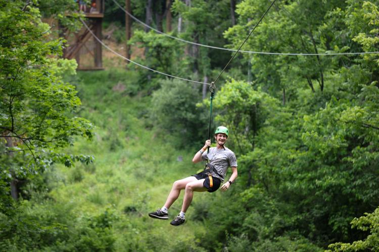 Cat Camp participant swings on zipline