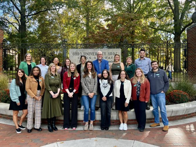 Scripps Young Alumni Council members stand together in front of the College Gate and the College Green