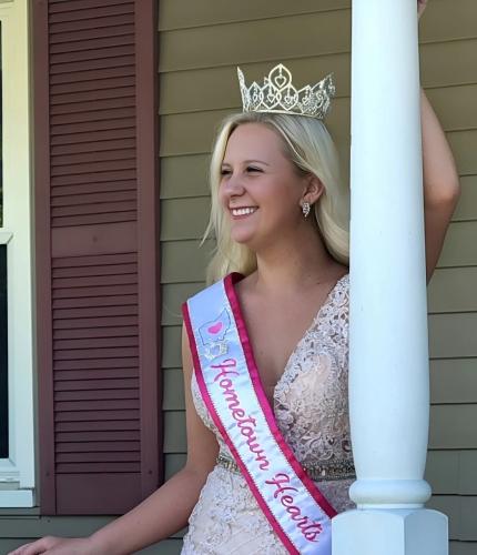 Sydney Bush is shown wearing her pageant crown and ribbon from the Hometown Hearts competition